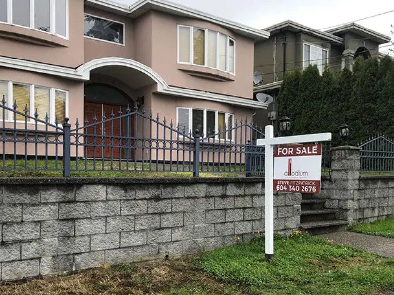 A house with a for sale sign in front of it.