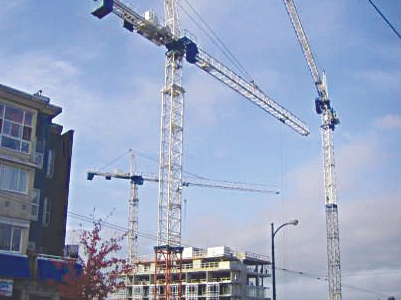 A group of cranes in front of some buildings.