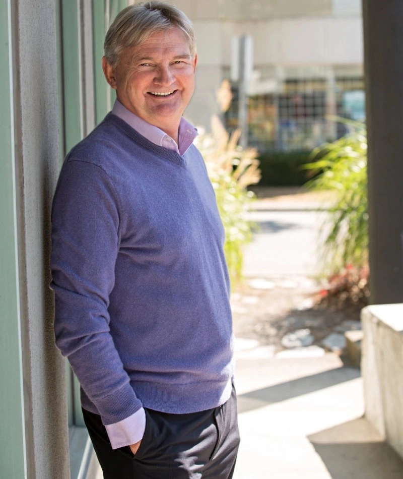 A man standing outside of a building wearing a sweater.